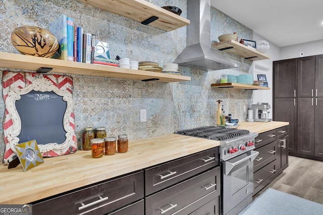 kitchen featuring open shelves, high end stainless steel range oven, butcher block countertops, and wall chimney exhaust hood