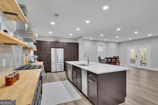 kitchen featuring visible vents, light wood-style flooring, stainless steel appliances, and a sink