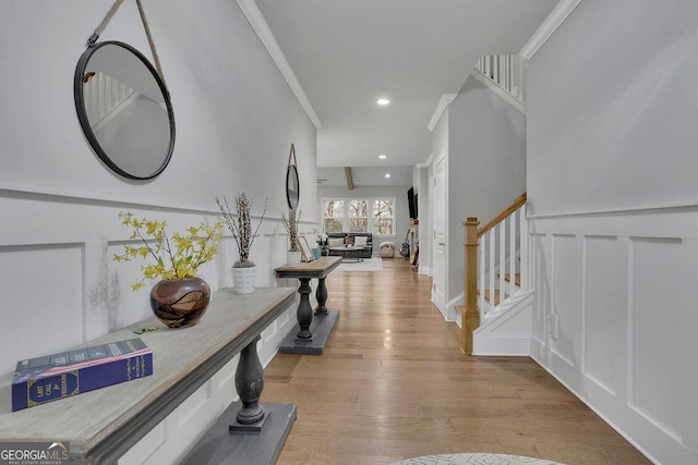 foyer with wood finished floors, recessed lighting, ornamental molding, stairs, and a decorative wall