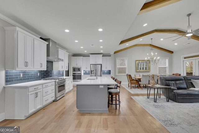 kitchen with light countertops, vaulted ceiling, stainless steel appliances, wall chimney exhaust hood, and a sink