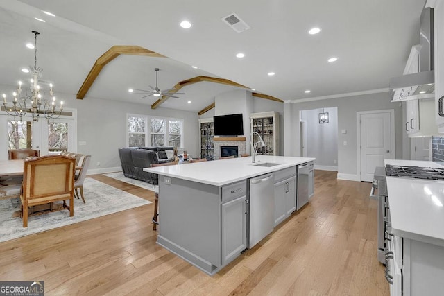 kitchen with a sink, stainless steel appliances, vaulted ceiling, light countertops, and gray cabinetry