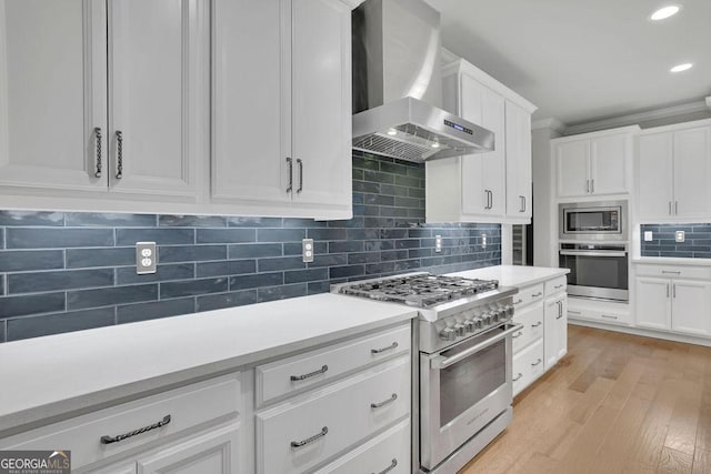 kitchen featuring tasteful backsplash, stainless steel appliances, wall chimney exhaust hood, and light countertops