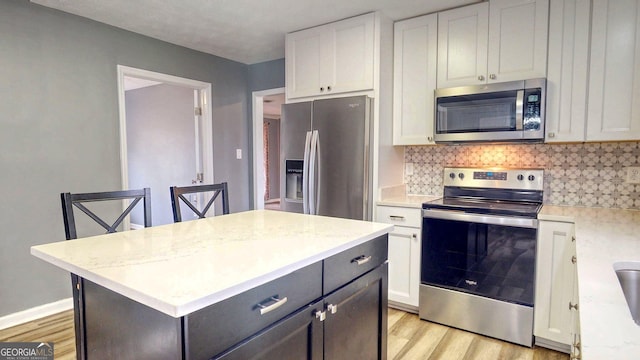 kitchen with white cabinetry, light wood-style flooring, backsplash, and stainless steel appliances