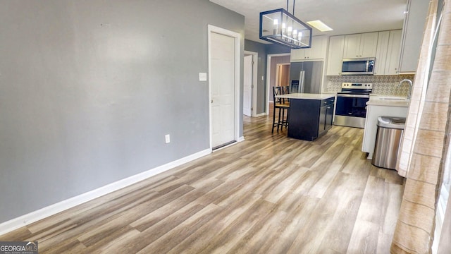 kitchen with a sink, decorative backsplash, light countertops, stainless steel appliances, and a kitchen breakfast bar