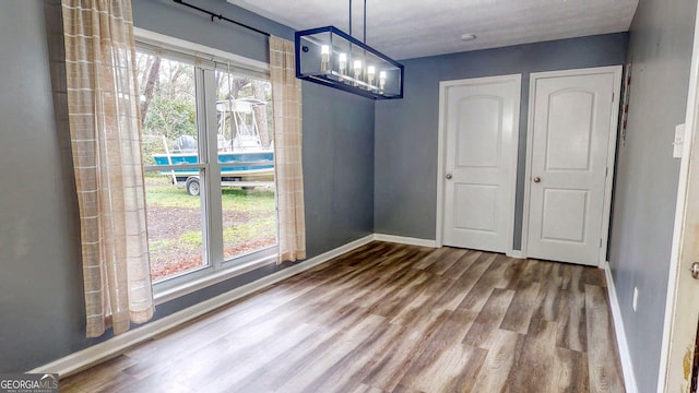 unfurnished dining area with wood finished floors and baseboards