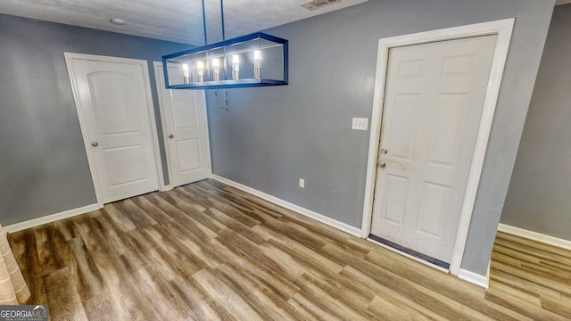 unfurnished dining area with visible vents, wood finished floors, and baseboards