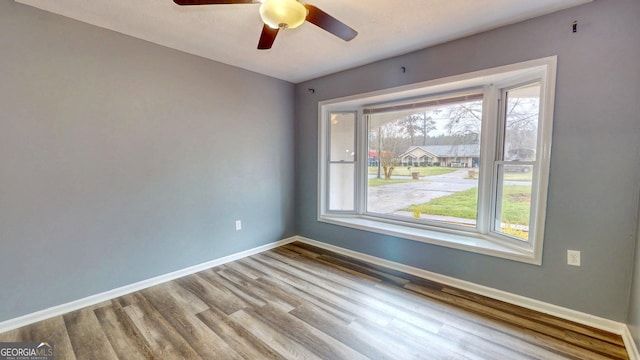 spare room featuring ceiling fan, baseboards, and wood finished floors