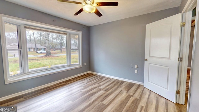 empty room featuring baseboards, light wood-style floors, and a ceiling fan