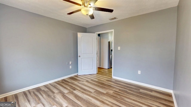 unfurnished room with visible vents, ceiling fan, baseboards, and wood finished floors