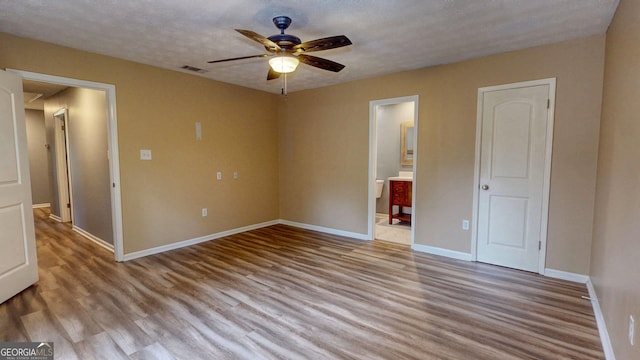 unfurnished bedroom with baseboards, visible vents, attic access, a textured ceiling, and light wood-type flooring