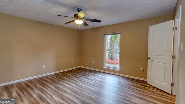 empty room featuring ceiling fan, baseboards, and wood finished floors