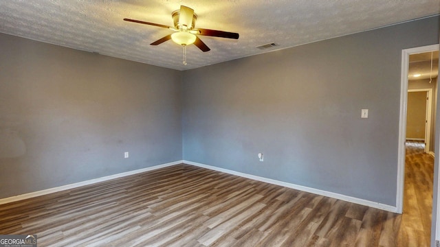 empty room featuring attic access, wood finished floors, baseboards, and a textured ceiling