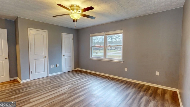 unfurnished bedroom featuring ceiling fan, wood finished floors, baseboards, and a textured ceiling