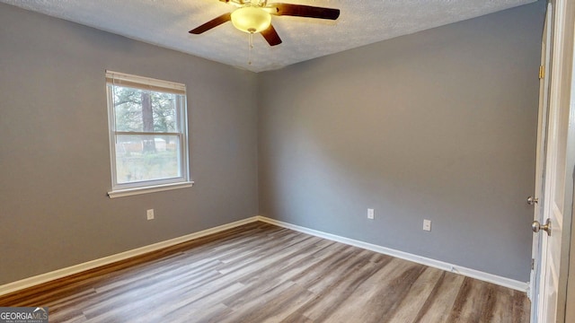 unfurnished room with ceiling fan, wood finished floors, baseboards, and a textured ceiling