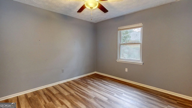 spare room with ceiling fan, baseboards, a textured ceiling, and wood finished floors