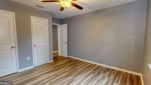 unfurnished bedroom with visible vents, baseboards, a textured ceiling, and wood finished floors