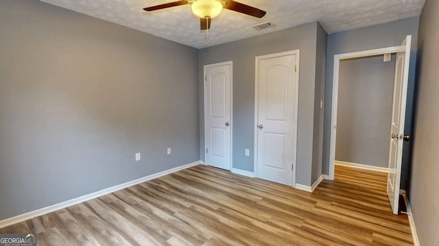 unfurnished bedroom with visible vents, baseboards, wood finished floors, a textured ceiling, and a ceiling fan