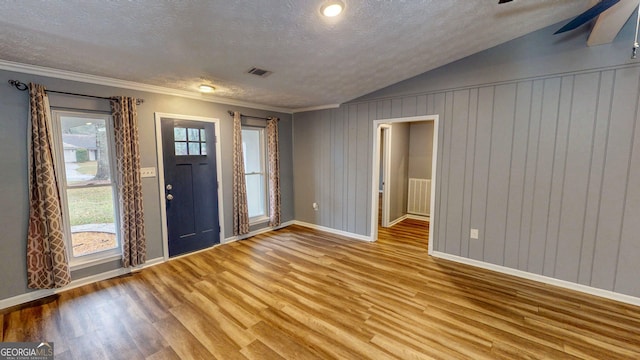 foyer entrance featuring visible vents, a textured ceiling, wood finished floors, and vaulted ceiling