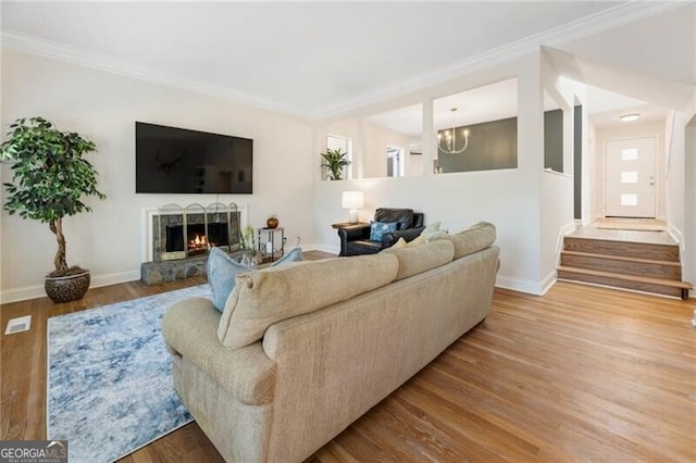 10 Colony Ridge Dr, Alpharetta, GA 30022 - living area with a warm lit fireplace, wood finished floors, ornamental molding, a chandelier, and stairway
