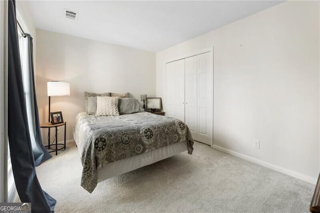 carpeted bedroom featuring baseboards, visible vents, and a closet