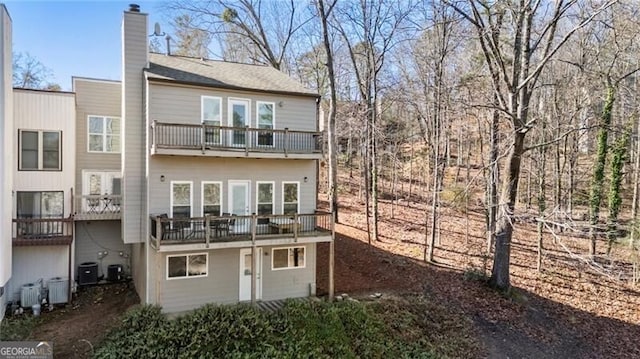 rear view of property featuring central AC unit and a chimney