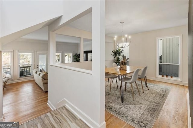 dining room with a notable chandelier, light wood-style flooring, and baseboards