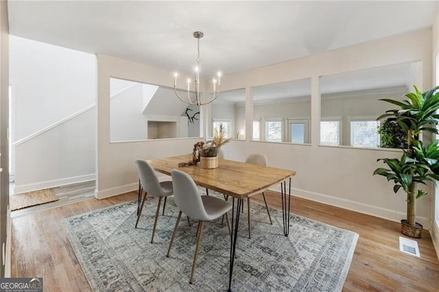 dining room featuring a notable chandelier, visible vents, baseboards, and wood finished floors