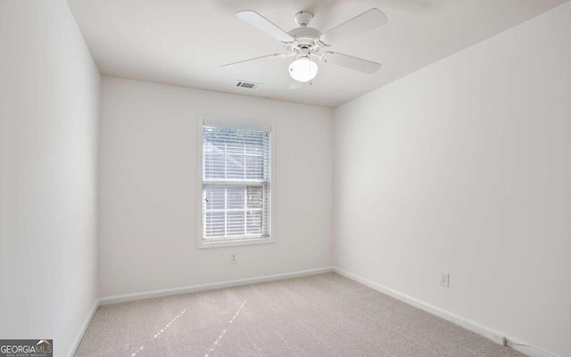 spare room with a ceiling fan, visible vents, carpet, and baseboards