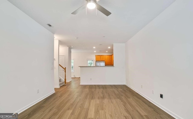unfurnished living room featuring ceiling fan, visible vents, baseboards, recessed lighting, and wood finished floors