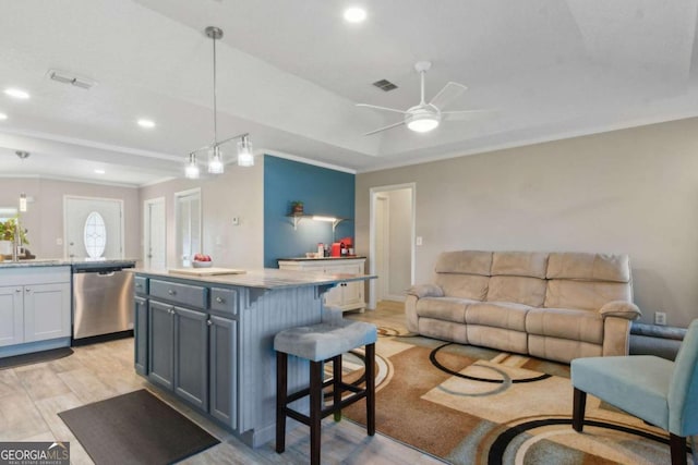 living area with a raised ceiling, recessed lighting, visible vents, and ceiling fan