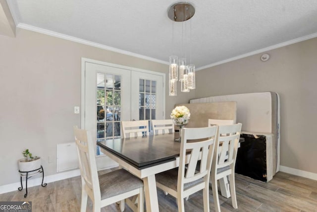 dining space featuring light wood-type flooring, baseboards, a notable chandelier, and crown molding