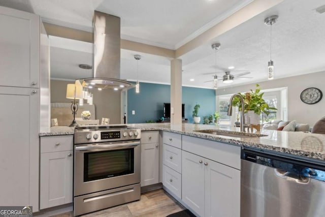 kitchen with light stone countertops, decorative light fixtures, island exhaust hood, stainless steel appliances, and a sink