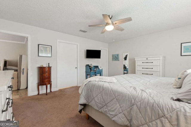 bedroom featuring a textured ceiling, a ceiling fan, visible vents, and light carpet