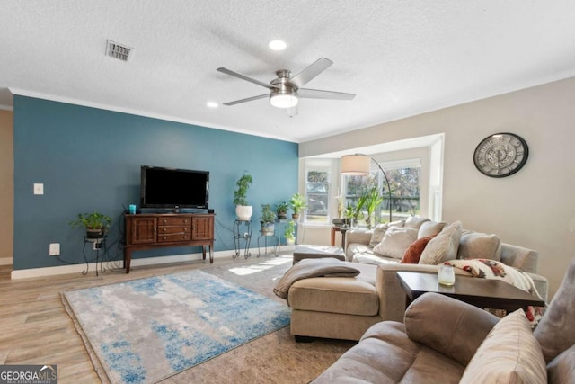 living room with crown molding, baseboards, and a textured ceiling