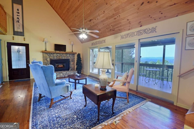 living room with wood finished floors, baseboards, high vaulted ceiling, a stone fireplace, and wood ceiling