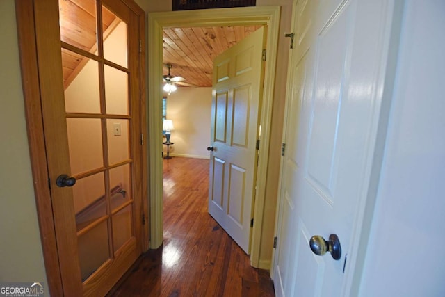 hallway with dark wood finished floors, wooden ceiling, and baseboards