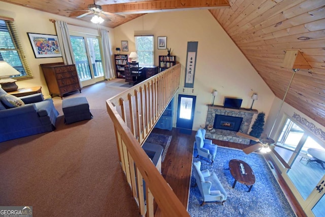 living room featuring beamed ceiling, high vaulted ceiling, a ceiling fan, a fireplace, and wood ceiling