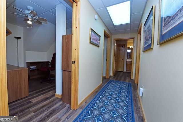 hallway with baseboards, a paneled ceiling, and wood finished floors