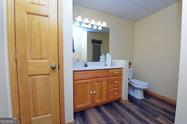 bathroom featuring toilet, vanity, baseboards, and wood finished floors