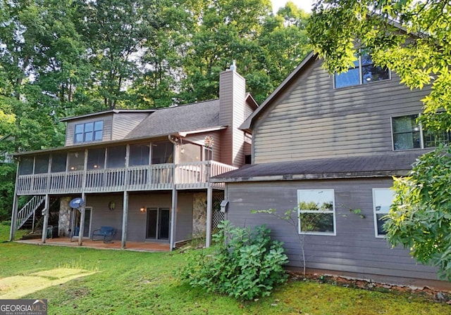 back of property with a yard, a sunroom, a chimney, stairs, and a patio area