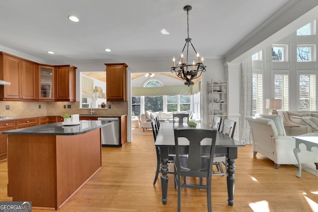 kitchen featuring stainless steel dishwasher, crown molding, a notable chandelier, brown cabinets, and a center island