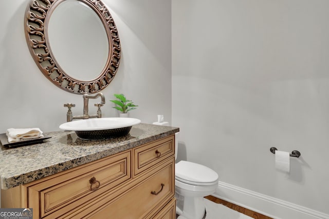 bathroom with baseboards, toilet, wood finished floors, and vanity