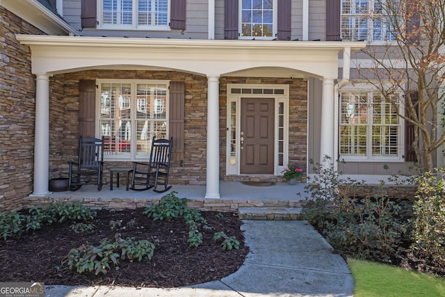 view of exterior entry with covered porch and stone siding