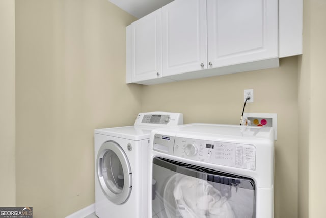 washroom featuring baseboards, cabinet space, and washing machine and dryer