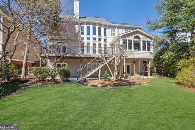 rear view of property featuring stairs, a deck, a lawn, and a sunroom