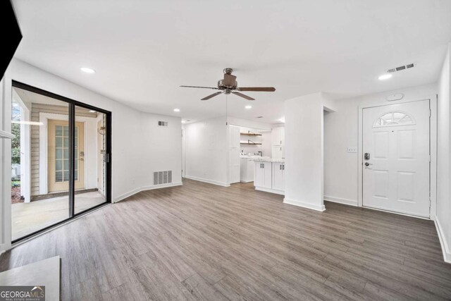 unfurnished living room featuring wood finished floors, visible vents, and baseboards