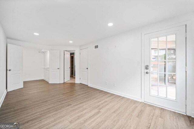 unfurnished room featuring plenty of natural light, wood finished floors, visible vents, and baseboards