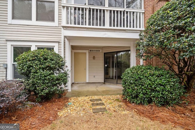property entrance with a balcony and brick siding