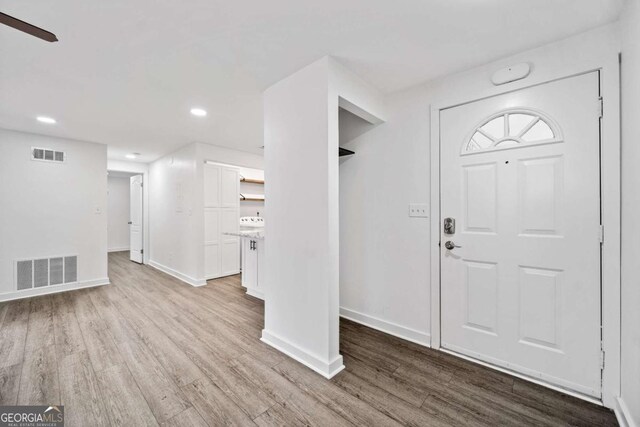 foyer with wood finished floors, visible vents, and baseboards