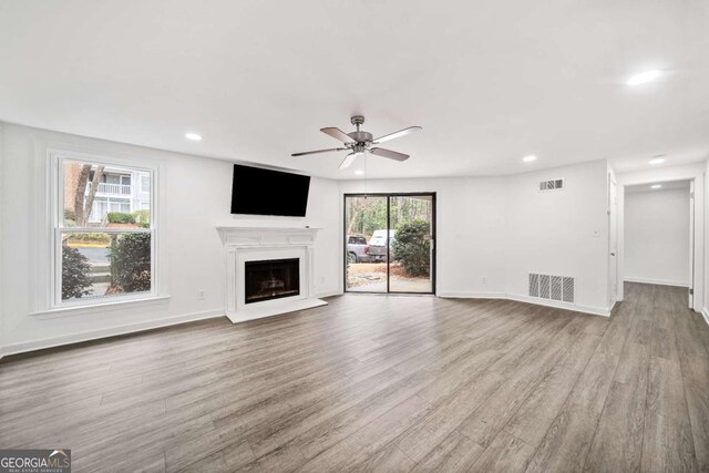 unfurnished living room with wood finished floors, visible vents, and a fireplace with raised hearth